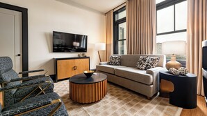 Ein modernes Wohnzimmer mit einer Couch, einem Sessel, einem Couchtisch und einem Fernseher an der Wand.