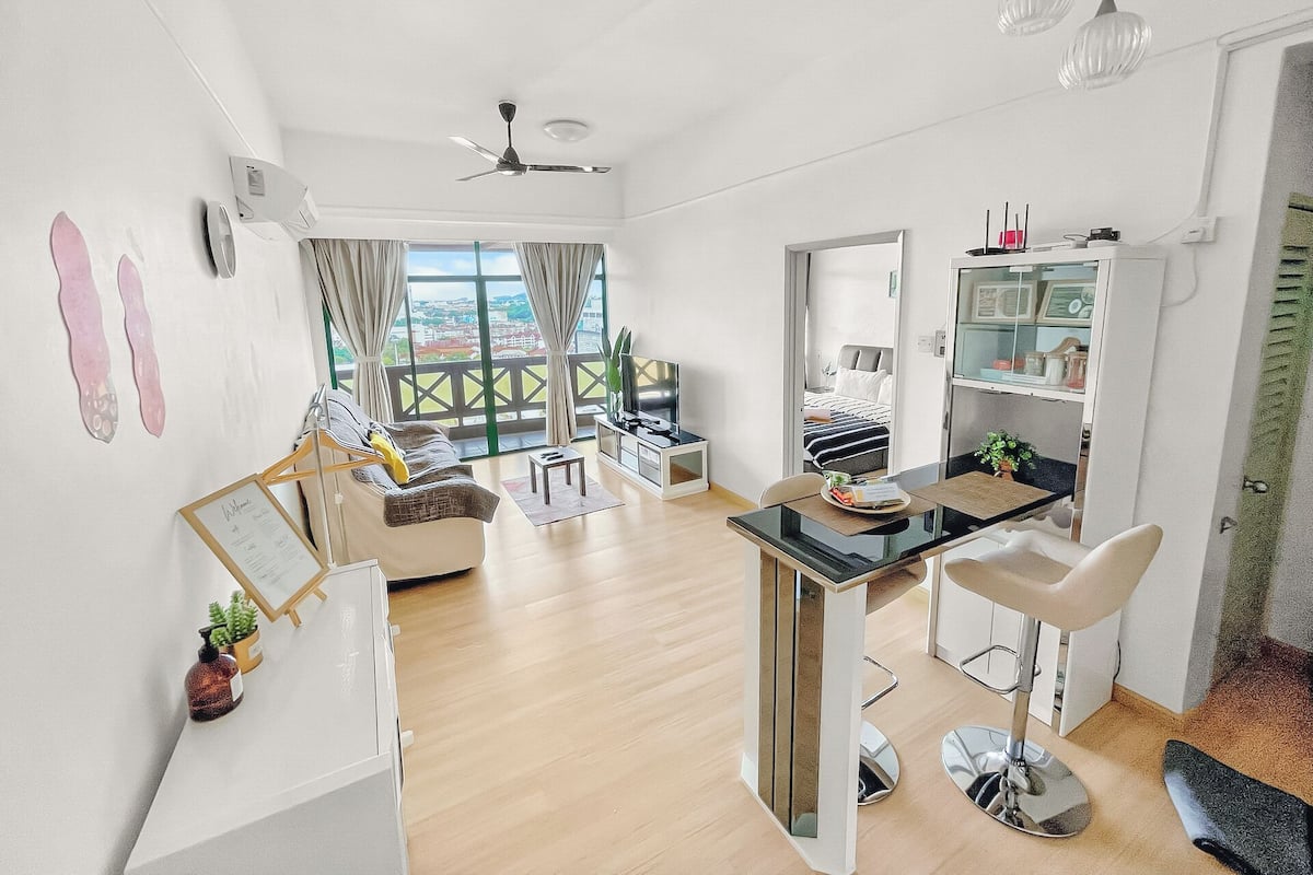 A modern living room with a sofa, a dining table, and a kitchen area.