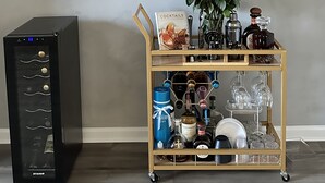 A minibar with a selection of beverages, a wine cooler, and a cart with a bouquet of red roses and a cocktail book. - Electric & Vibrant home 15 min from Downtown ATL (Decatur)
