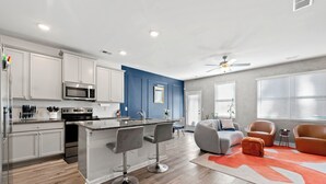 A modern kitchen with white cabinets, a built-in microwave, and a central island with bar stools. - Electric & Vibrant home 15 min from Downtown ATL (Decatur)