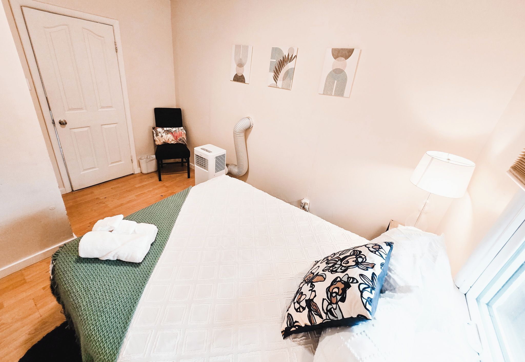 A bedroom with a bed, a chair, a heater, and wall art.
