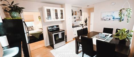 Una cocina moderna con comedor, piso de madera y una planta colgante.