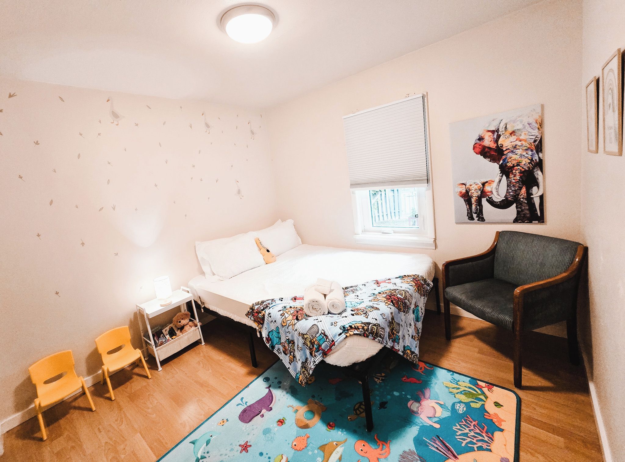 Une chambre à coucher avec un lit, une chaise, une petite table et une fenêtre.