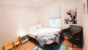 Un dormitorio con una cama, una silla, una mesita y una ventana.