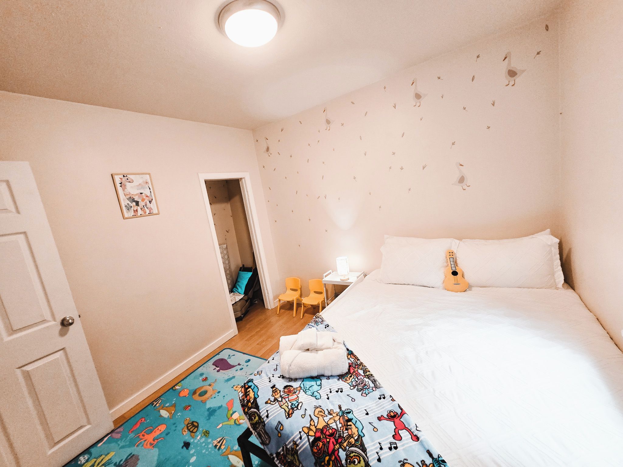 Un dormitorio con cama, escritorio, silla y una alfombra colorida.