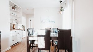 A modern dining area with a wooden table and chairs, a white cabinet with drawers, and a hanging plant. - Stay & Play - Central Family Friendly (Calgary)