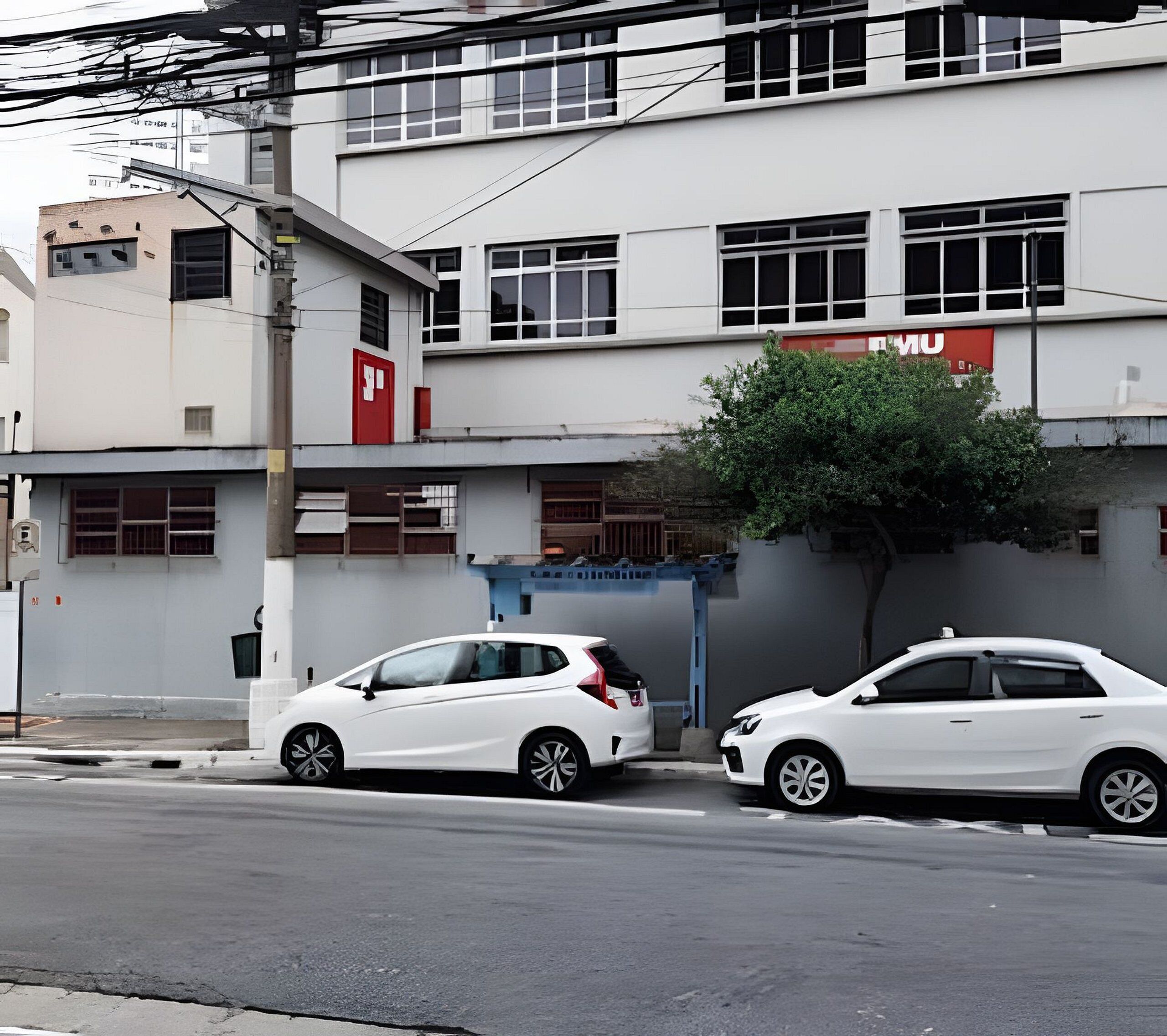 A street view with two white cars parked on the side of the road, a building with a red sign, and a tree in front of the building.