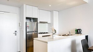A modern kitchen with white cabinetry, a stainless steel refrigerator, a gas stove, and a sink.