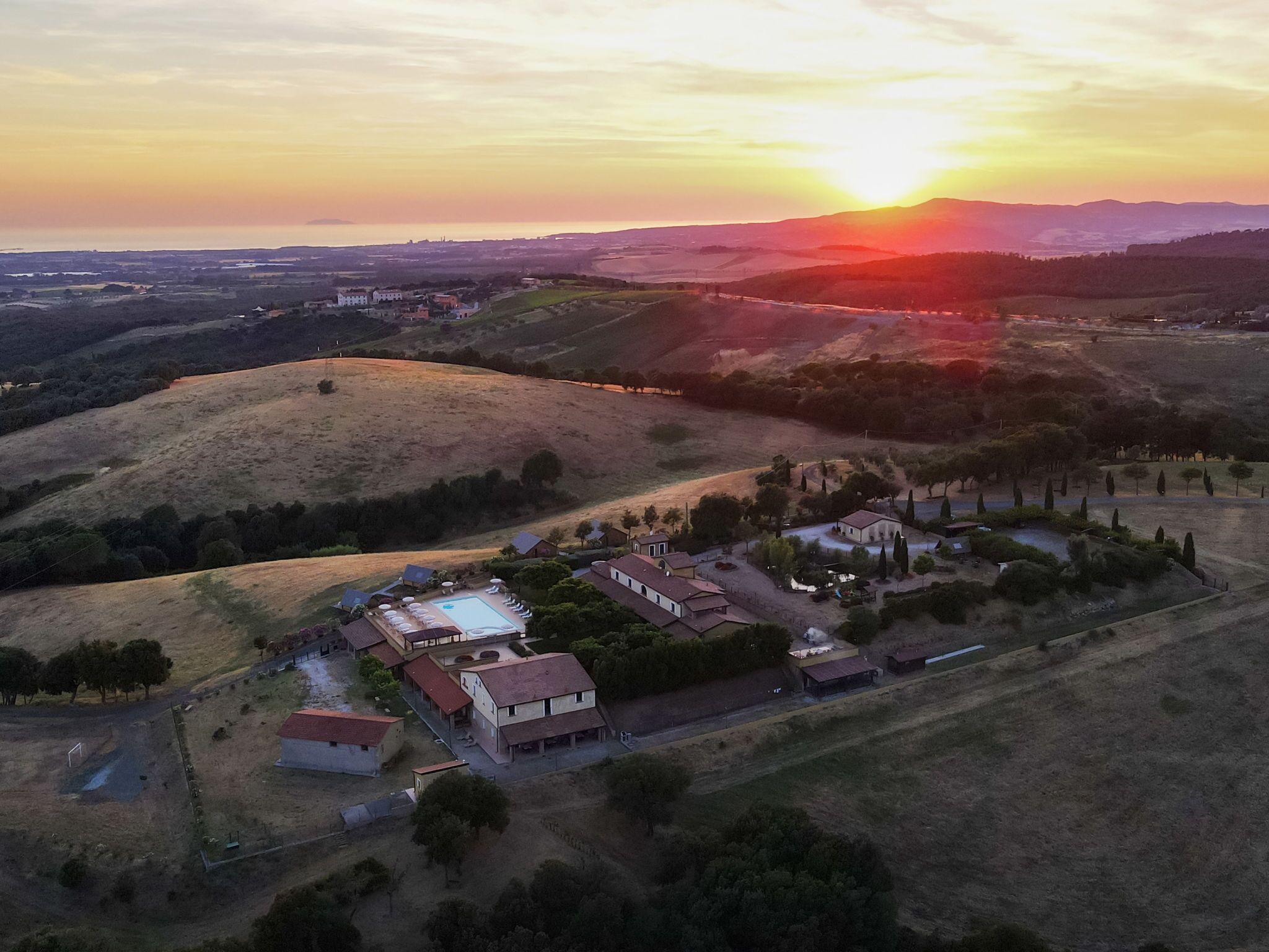 An aerial view of a residential area with houses, a swimming pool, and rolling hills.
