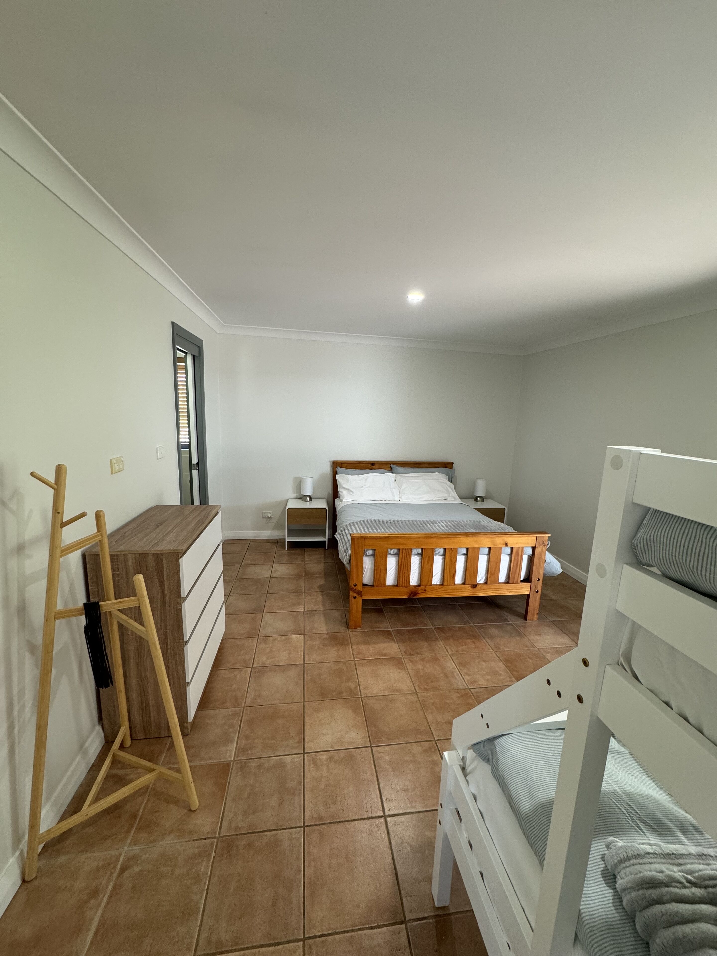 A bedroom with a wooden bed, a small bedside table, a wardrobe, and a wooden ladder.
