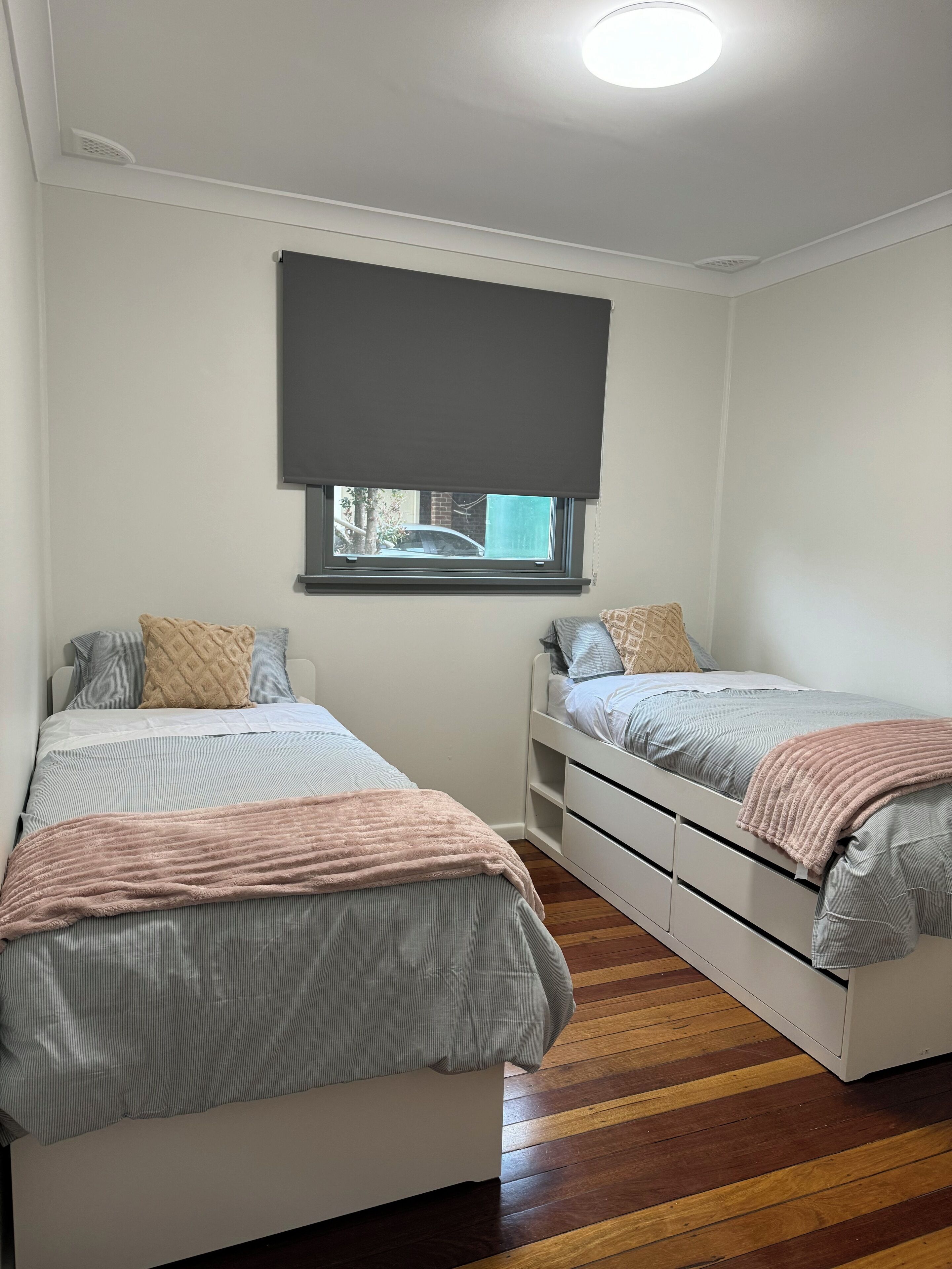 Een slaapkamer met twee bedden, een raam met uitzicht en een plafondlamp.