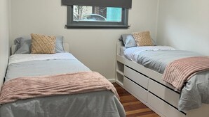 Quarto com duas camas, uma janela com vista para o exterior e uma luminária no teto.