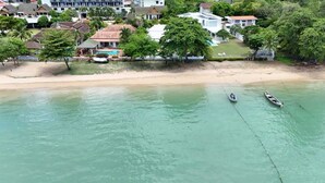 Une zone côtière avec une plage de sable, deux bateaux et des immeubles résidentiels dotés d’une piscine.