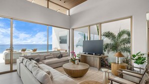 Un saló modern amb un televisor gran, seients confortables i vista a l'oceà.
