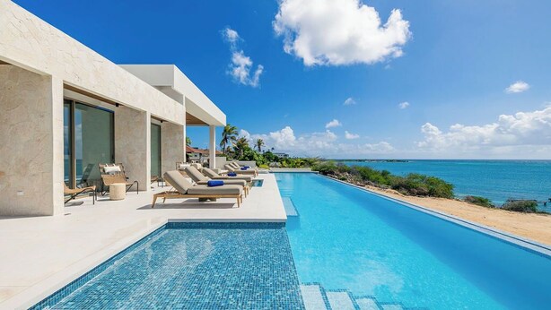 Una zona de piscina moderna amb gandules i una vista despejada de l'oceà.