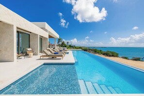 Ein moderner Poolbereich mit Liegestühlen und freiem Blick auf den Ozean.