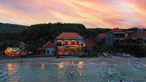 A beachfront property with multiple buildings, a dining area, and boats. - Barton Beach Inn (Penida Island)