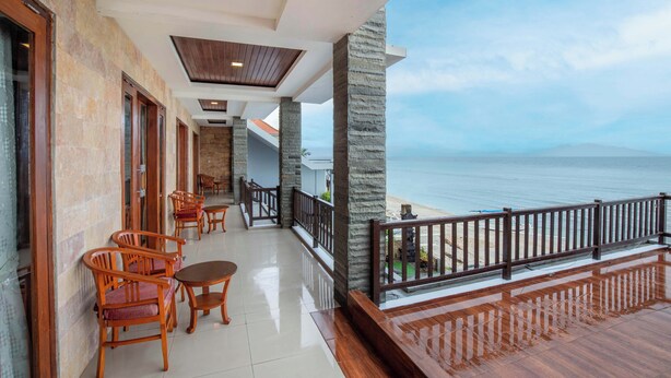 A balcony with wooden furniture and a view of the sea. - Barton Beach Inn (Penida Island)
