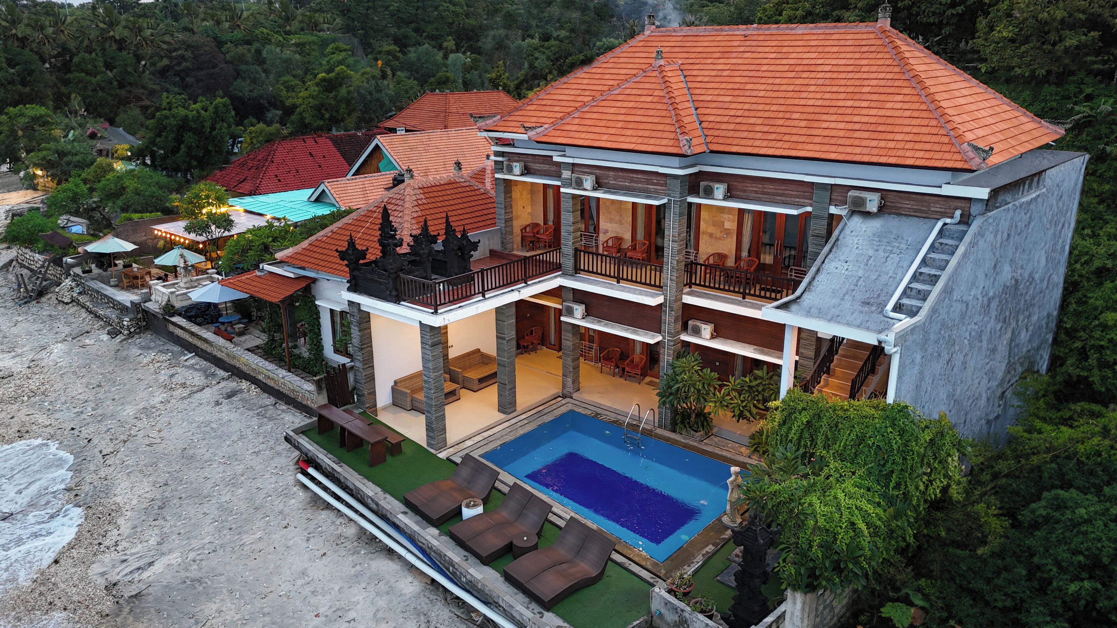 A multi-story building with a swimming pool, balconies, and outdoor seating areas.