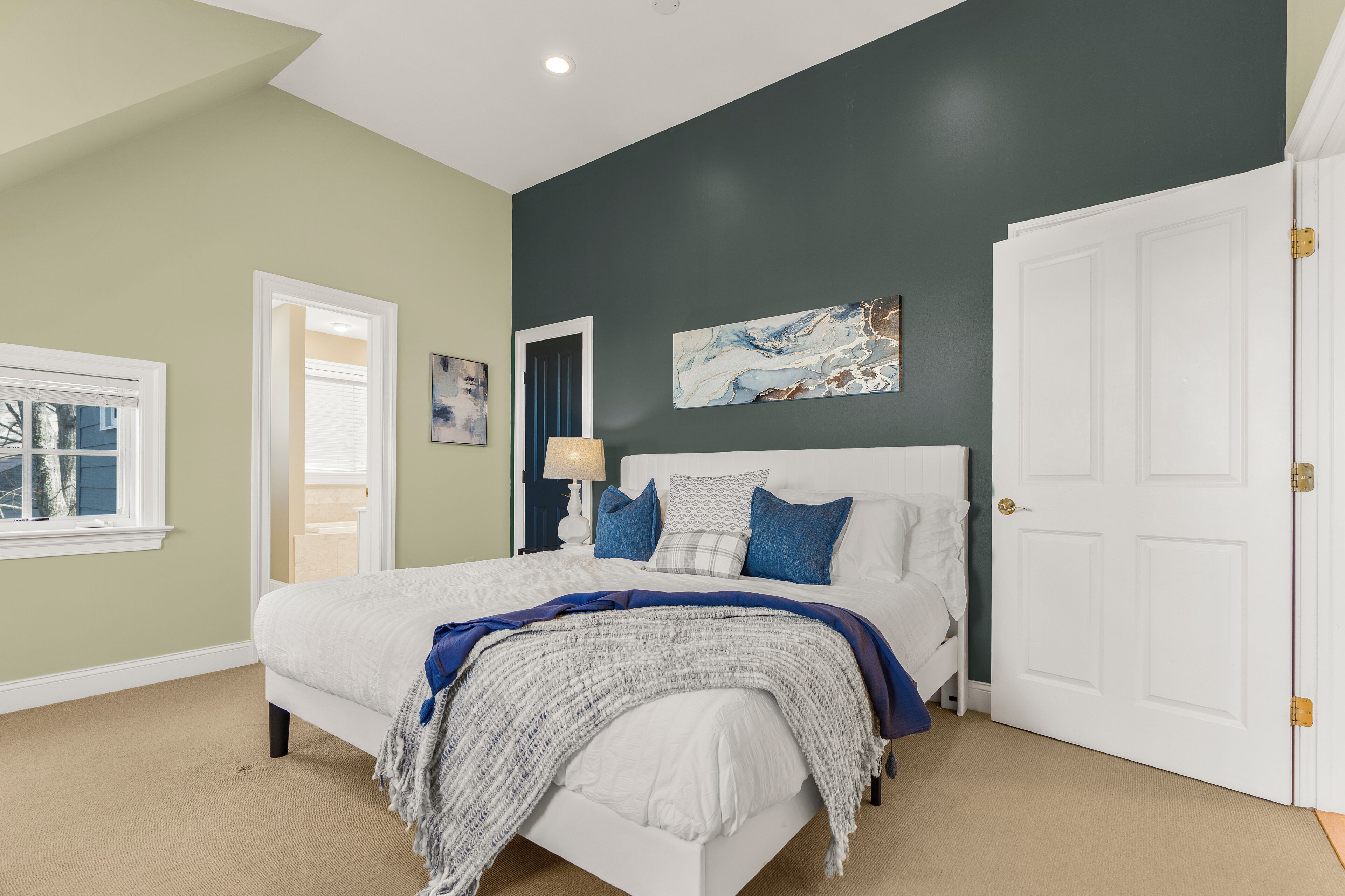A bedroom with a bed, a nightstand, a lamp, and a door.