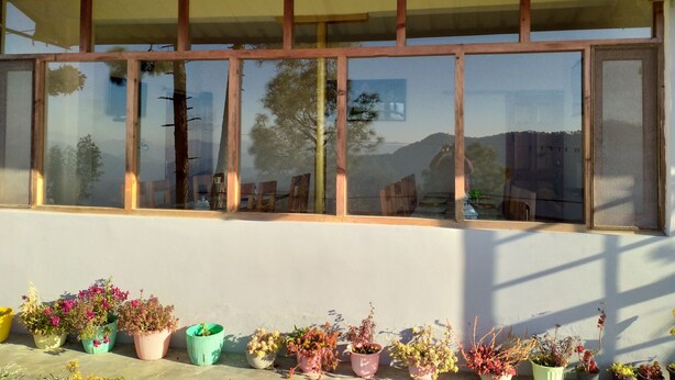 A building with a large window and multiple potted plants in front. - Binsar View Homestay (Almora)