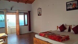 A bedroom with a wooden bed, a view of the sea through a large window, and a door leading outside. - Binsar View Homestay (Almora)