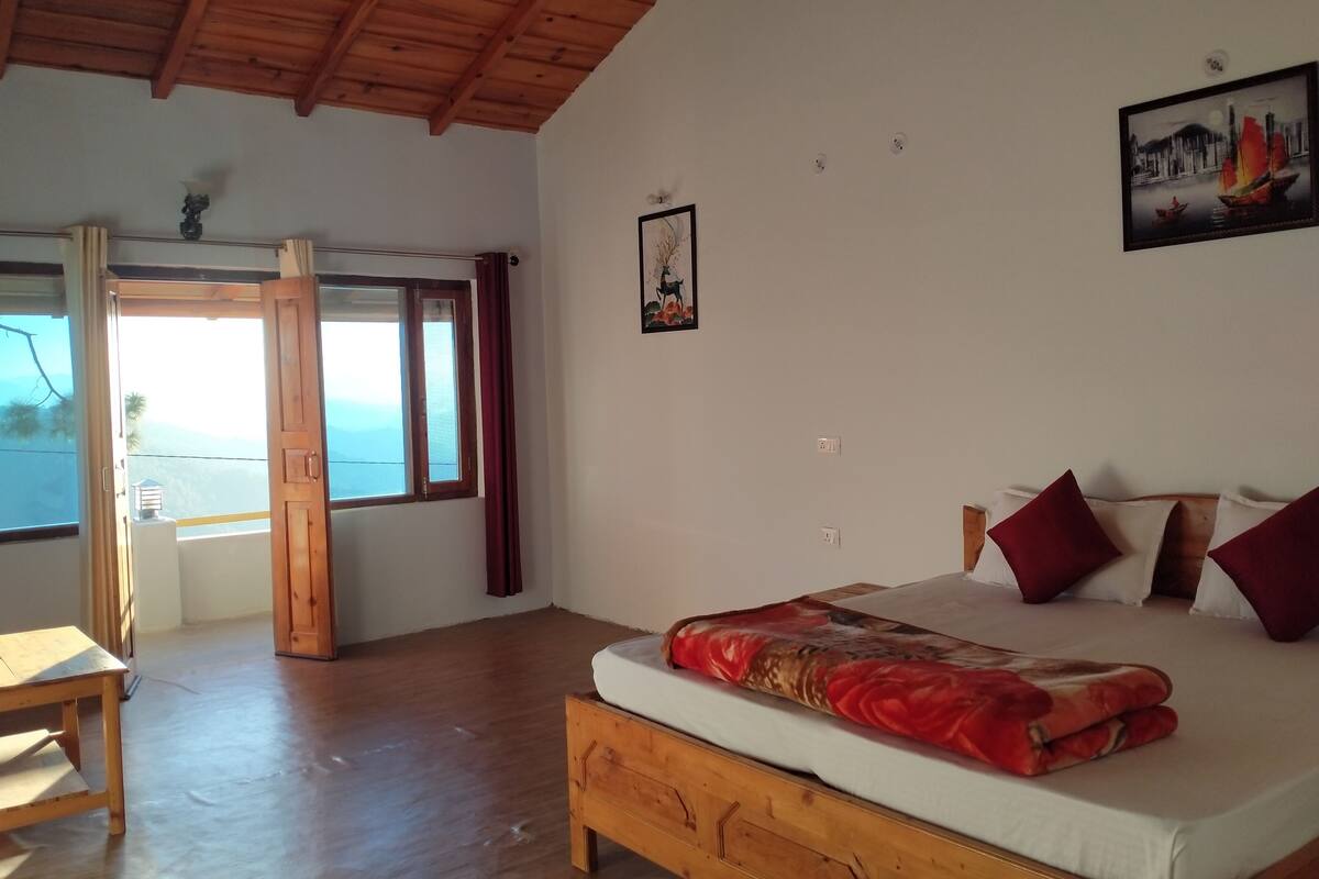 A bedroom with a wooden bed, a view of the sea through a large window, and a door leading outside.