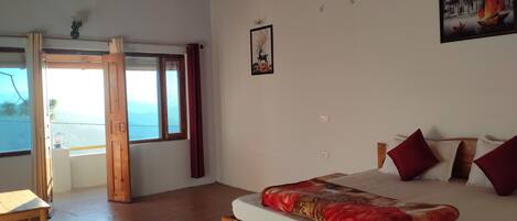 A bedroom with a wooden bed, a view of the sea through a large window, and a door leading outside.