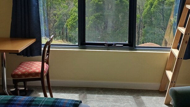 Un dormitorio con un ventanal que ofrece vistas a un paisaje boscoso.