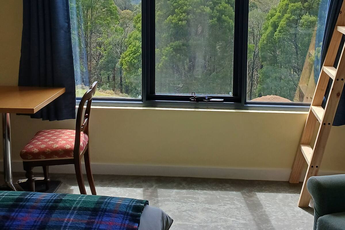 Un dormitorio con un ventanal que ofrece vistas a un paisaje boscoso.