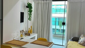 En moderne stue med spiseplads, en sofa og en balkon med gardiner.