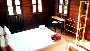A wooden cabin room with a bed, a desk, and a chair.