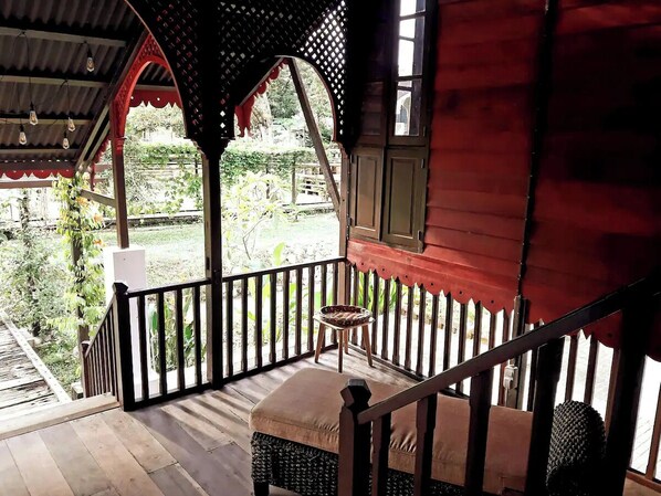 A wooden deck with a railing, a small table, and a cushioned bench.