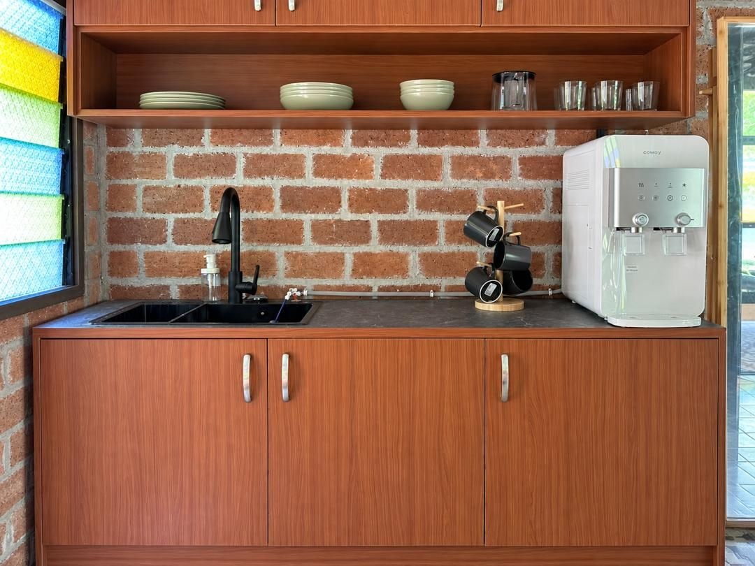 Eine kompakte Küche mit Ziegelrückwand, einer Kaffeemaschine und einem Wasserspender.