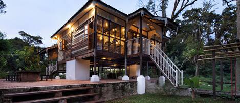 A wooden house with a balcony and a staircase leading to the upper level.