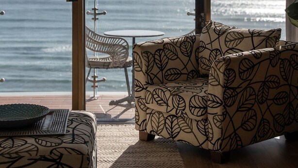 Un balcon avec vue sur l’océan, une table et deux canapés à motifs.