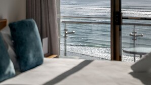 Une chambre avec une grande fenêtre donnant sur l’océan, un lit et une vue sur la mer.