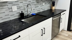 Una cocina moderna con armarios blancos, encimeras negras y salpicadero de azulejos.