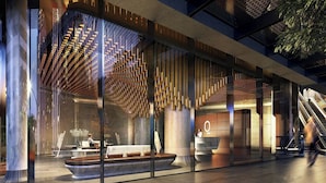 A modern hotel lobby with a central seating area, a reception desk, and an escalator.