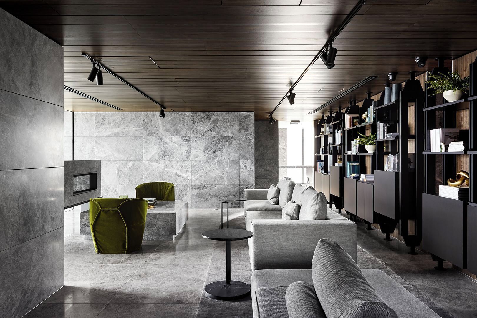 Un interior moderno con una pared de mármol, una silla verde, un sofá gris y una estantería.