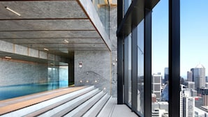 A modern building with a glass pool, a staircase, and a city view.