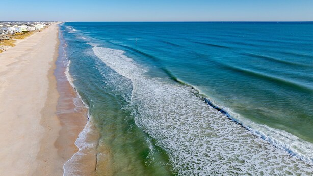 Una playa con agua azul cristalina y una orilla arenosa.