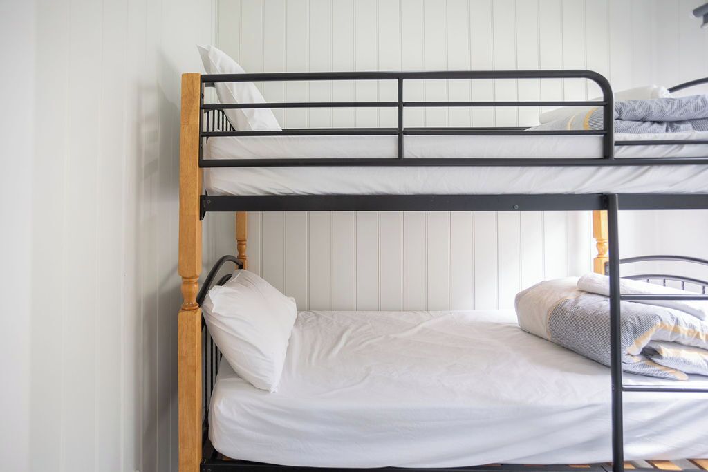 A bunk bed with white bedding and a wooden headboard.