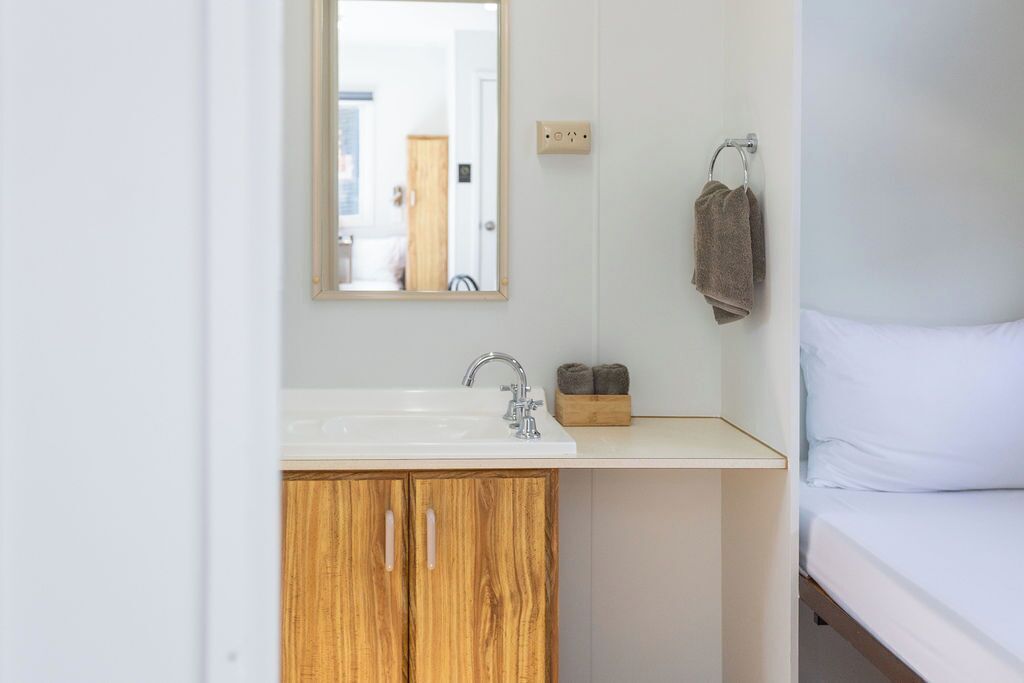 A bathroom with a white sink, wooden cabinets, a mirror, and a towel rack.