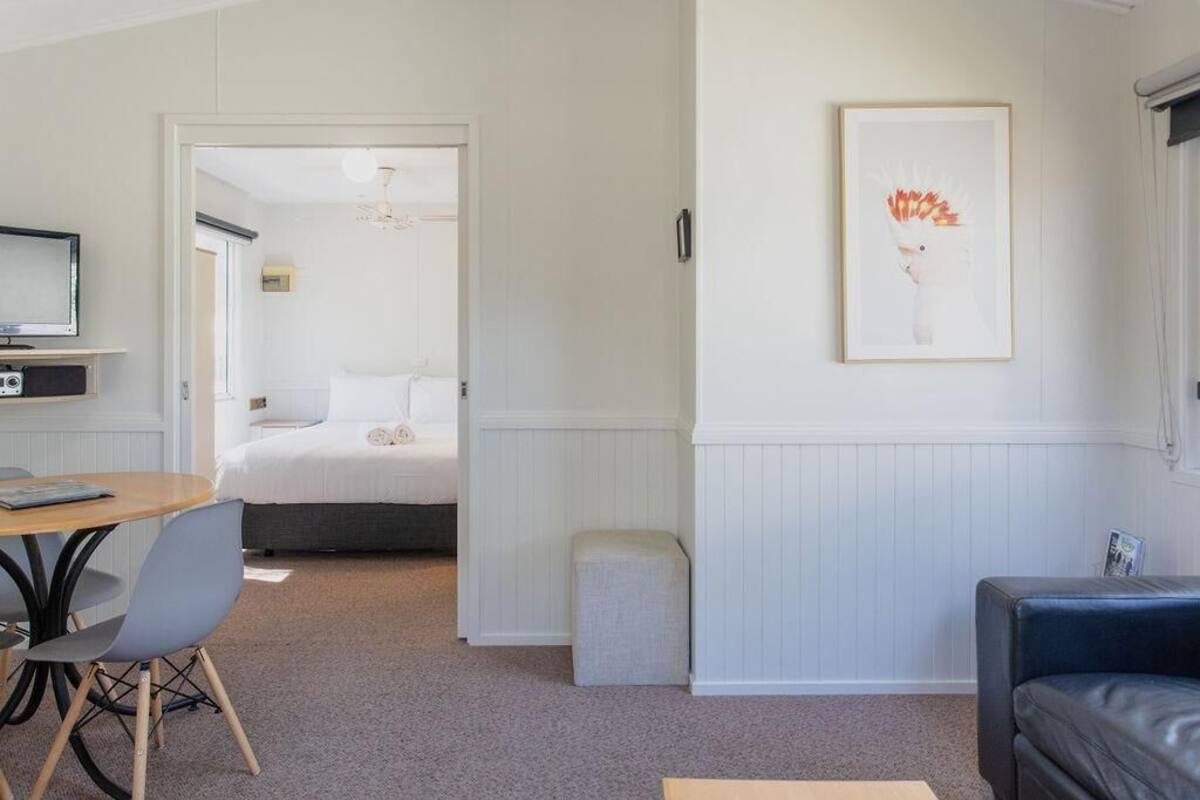 Ein Zimmer mit einem Bett, einem Schreibtisch mit Stuhl, einer Couch und einem gerahmten Bild an der Wand.