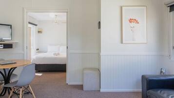 A room with a bed, a desk with a chair, a sofa, and a framed picture on the wall.