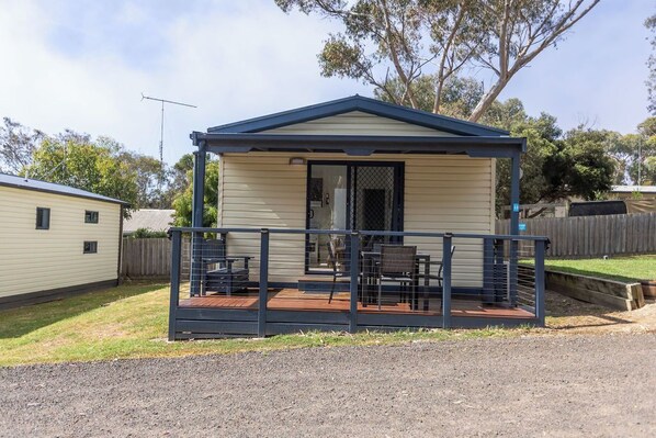 A small, single-story house with a porch and a covered outdoor seating area.