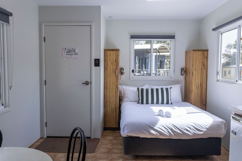 Een slaapkamer met een bed, een raam, een deur en een kleine tafel.