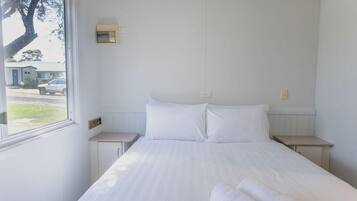 Un dormitorio con una cama grande, dos mesitas de noche, un ventanal y un termostato en la pared.