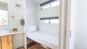 A compact room with a bunk bed, a small sink, and a mirror.
